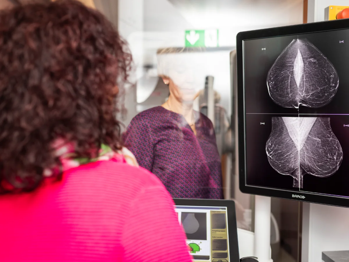 Klientin und Röntgenassistentin des Mammographie Screening Programms Niedersachsen Nordwest betrachten gemeinsam die Röntgenaufnahmen